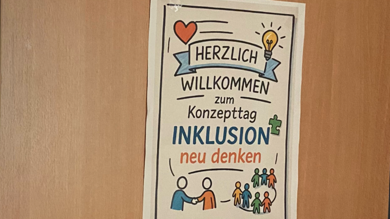 Auf dem Foto ist ein Plakat zu sehen, das an einer Tür oder Wand hängt. ?️ Was das Plakat sagt: Titel: HERZLICH WILLKOMMEN zum Konzepttag INKLUSION Untertitel: neu denken Bildelemente: Ein rotes Herz. Eine leuchtende Glühbirne (Symbol für eine neue Idee). Eine Sprechblase oder ein Banner mit der Aufschrift "HERZLICH WILLKOMMEN". Ein Puzzleteil (neben "INKLUSION"). Zwei Personen, die sich die Hand geben (symbolisiert Verbindung oder Zusammenarbeit). Eine Gruppe verschiedener, farbiger Strichmännchen (steht für Vielfalt und Gemeinschaft). Zusammenfassend: Es handelt sich um eine Einladung zu einem Konzepttag zum Thema Inklusion mit dem Motto, dieses Thema "neu zu denken". Sieht nach einem Tag voller Ideen aus – hoffentlich mit gutem Kaffee!