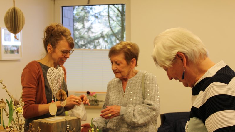 Das Bild zeigt zwei Bewohnerinnen die sich am Frühlingsmarkt an einem Stand etwas Deko kaufen.