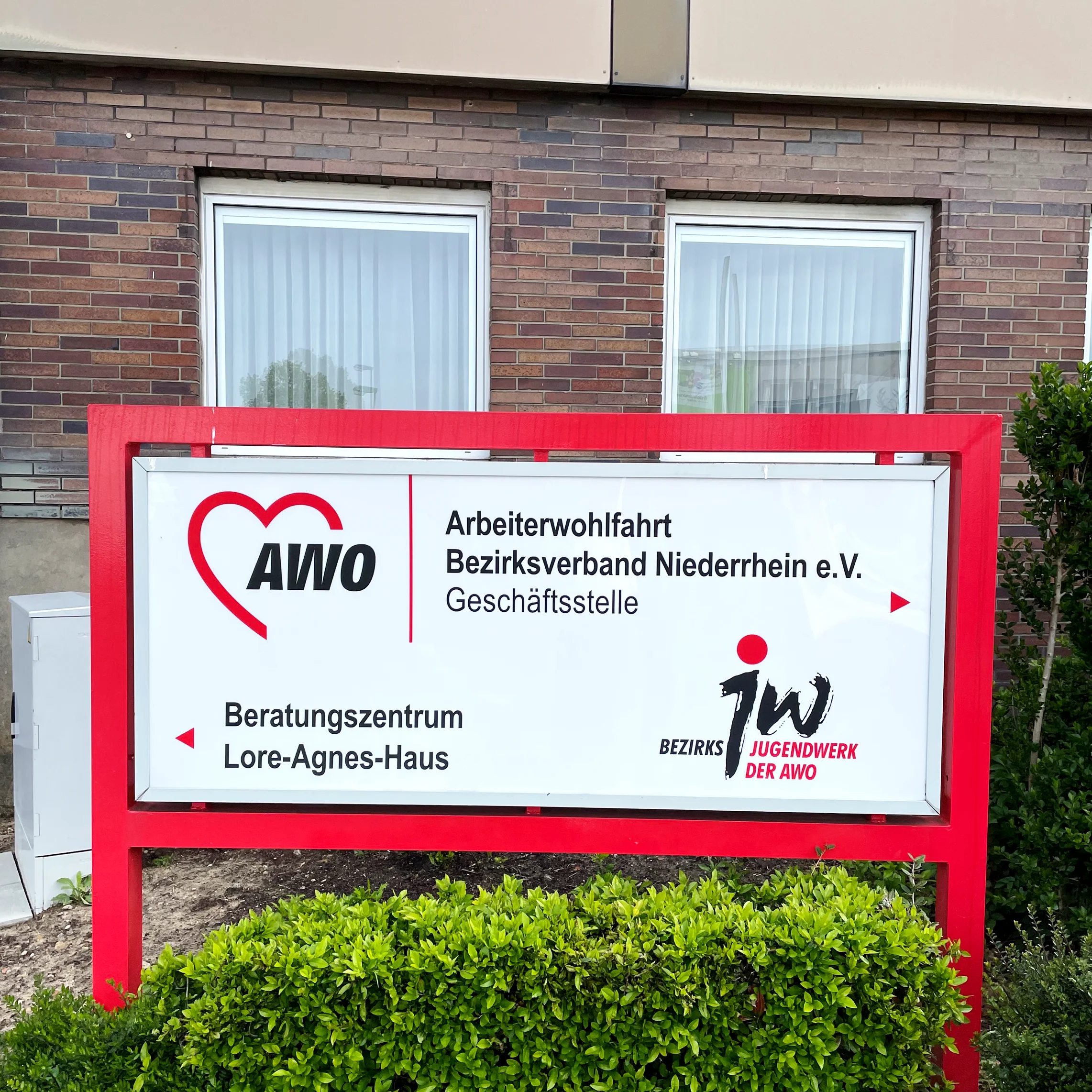 Das Foto zeigt ein Straßenschild, das auf die Geschäftsstelle der AWO hinweist.