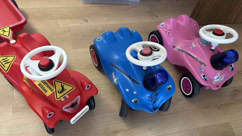 Das Bild zeigt die sogenannten Dienstfahrzeuge der Kolleg*innen. Es sind Bobbycars.