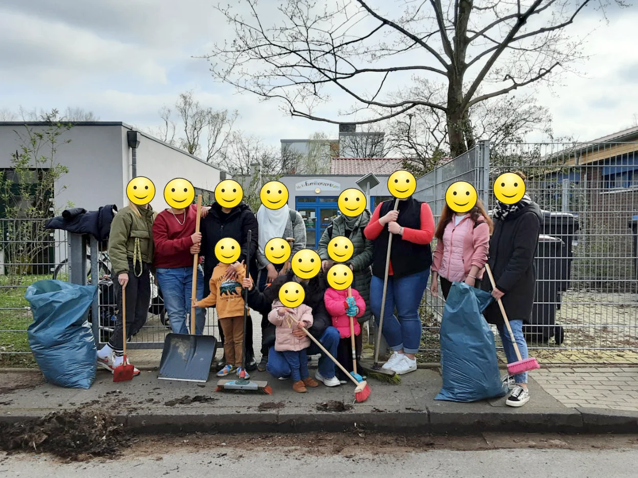 Das Foto zeigt Kinder, Eltern und Erzieher*innen mit Schaufeln und Besen vor der Kita
