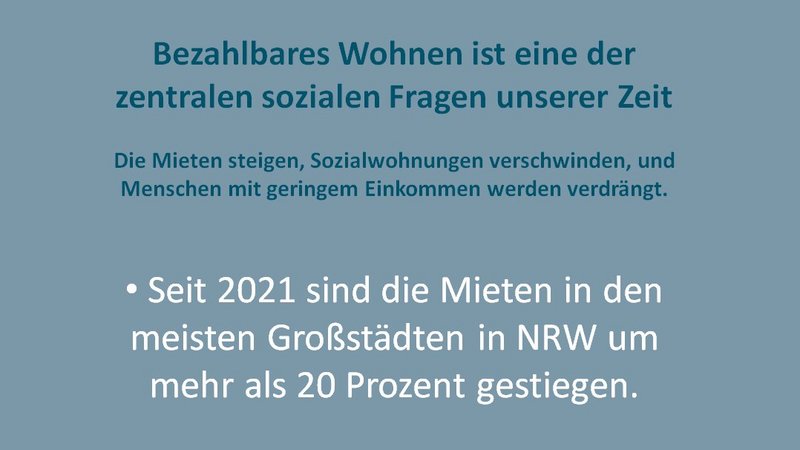 Das Foto zeigt ein Plakat mit dem Titel "Bezahlbares Wohnen ist eine der zentralen sozialen Fragen unserer Zeit". Es werden drei Hauptaussagen in Form von Bullet Points präsentiert: Seit 2021 sind die Mieten in den meisten Großstädten in Nordrhein-Westfalen (NRW) um mehr als 20 Prozent gestiegen. Der Bestand an Sozialwohnungen in NRW ist von 1,3 Millionen (1990) auf aktuell 422.000 gesunken. 2024 wurden in NRW 122.170 wohnungslose Menschen offiziell erfasst. Unterhalb des Textes befindet sich das Logo der Organisation "Wir wollen wohnen" und die zugehörige Webseite "www.wir-wollen-wohnen-nrw.de".