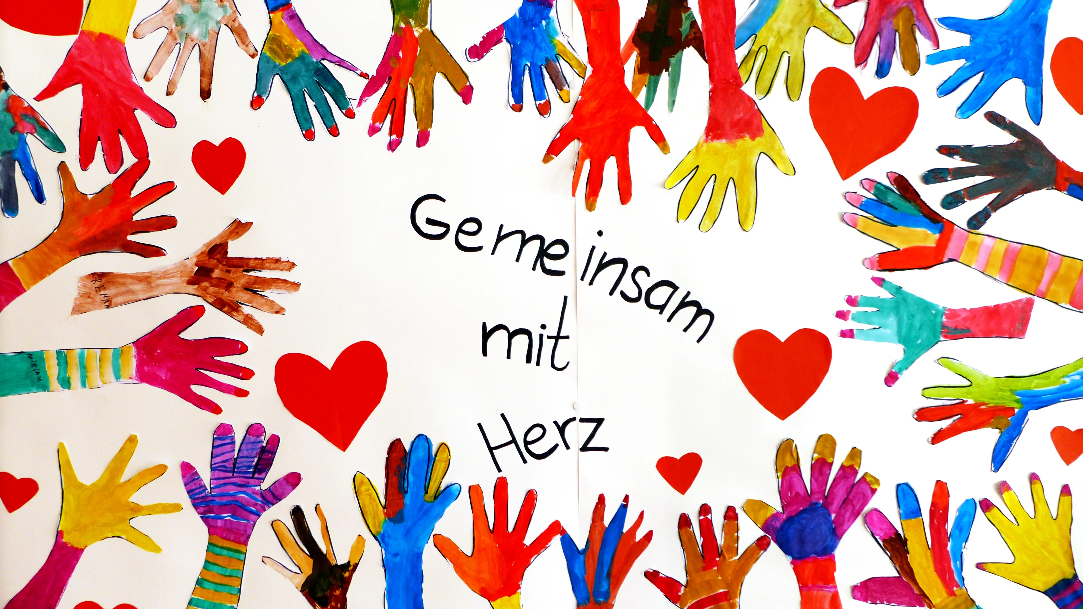 Gemaltes Bild "Gemeinsam mit Herz" Gemalte Kinderhände zeigen auf den Claim "Gemeinsam mit Herz"