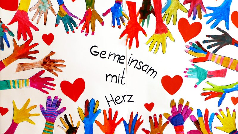 Gemalte Kinderhände zeigen auf den Claim "Gemeinsam mit Herz"
