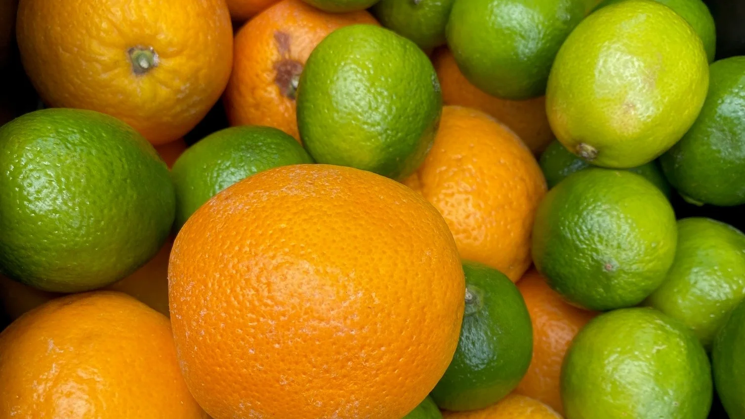 Auf diesen Bild sind viele Limetten und Orangen zu sehen.