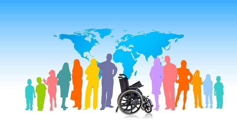 Auf dem Bild sind bunte Silhouetten von Menschen unterschiedlichen Alters zu sehen, die nebeneinander stehen. In der Mitte steht ein leerer Rollstuhl, im Hintergrund ist eine stilisierte Weltkarte vor blauem Himmel dargestellt.