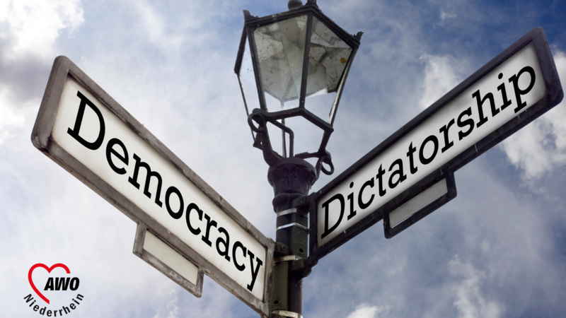 Das Foto zeigt eine Weggabelung mit den Straßenschildern "Democracy" und "Dictatorship"