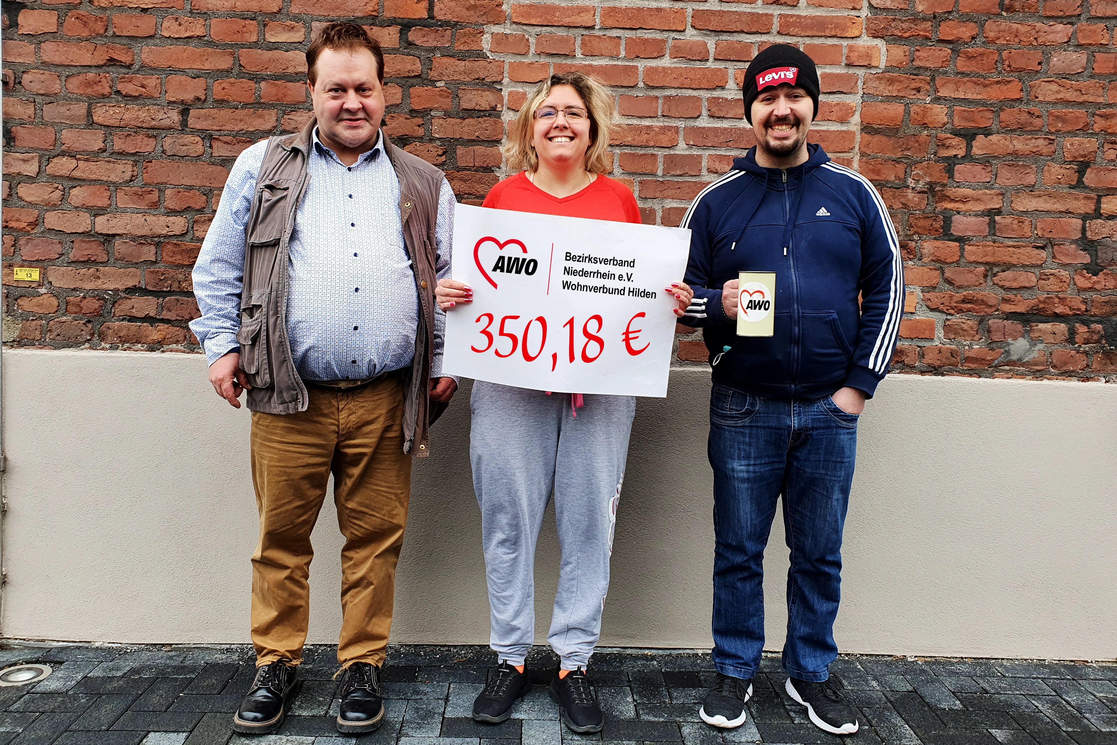 Das Foto zeigt Klient*innen des Wohnverbundes, die stolz ihre gesammelten Spenden präsentieren