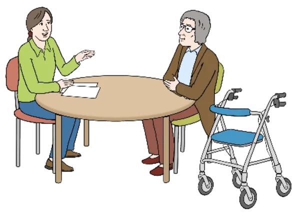 Das Foto zeigt zwei Menschen an Tisch. Daneben steht ein Rollator