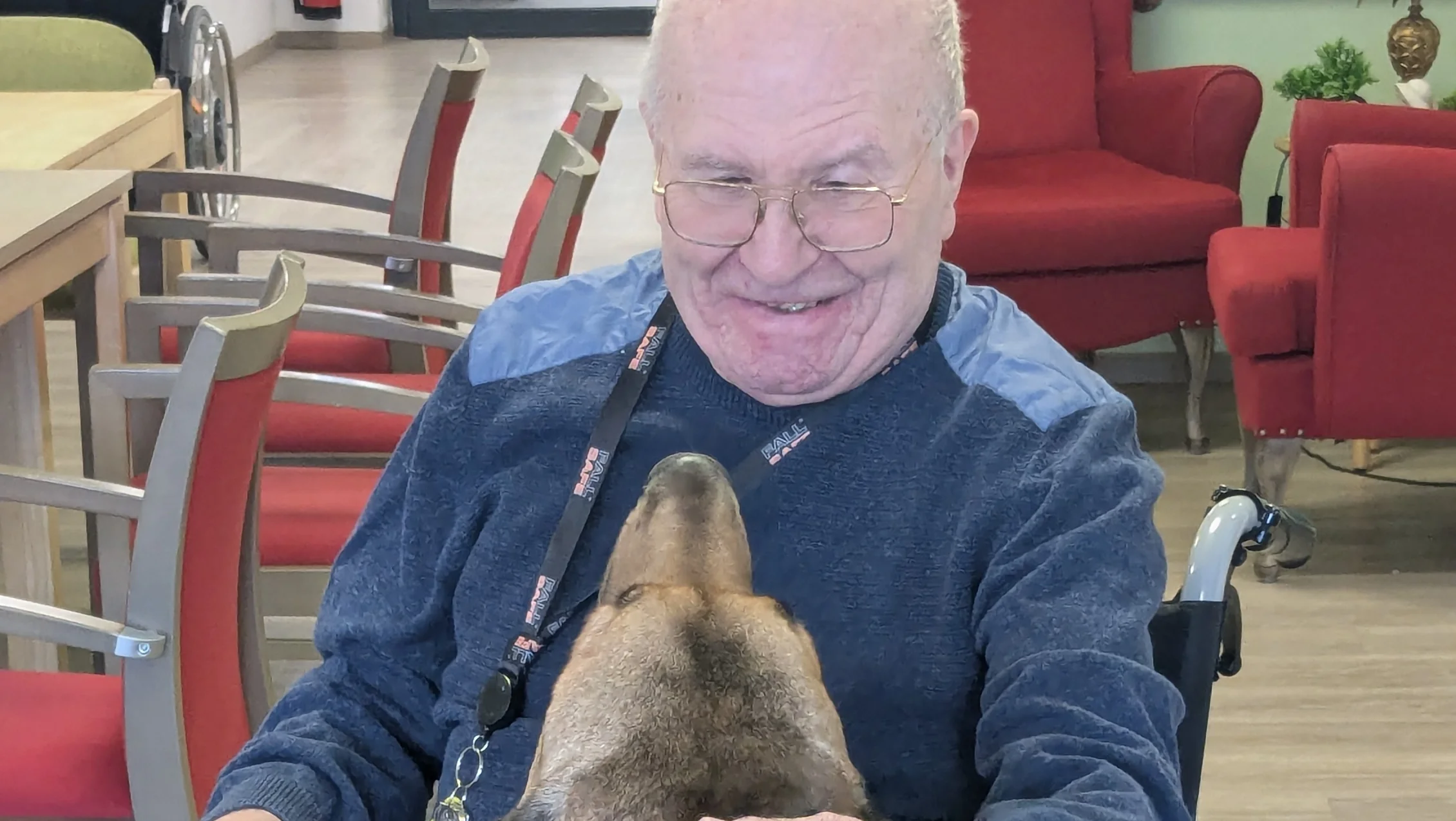 Das Bild zeigt einen Bewohner wie er liebevoll einen Hund streichelt.