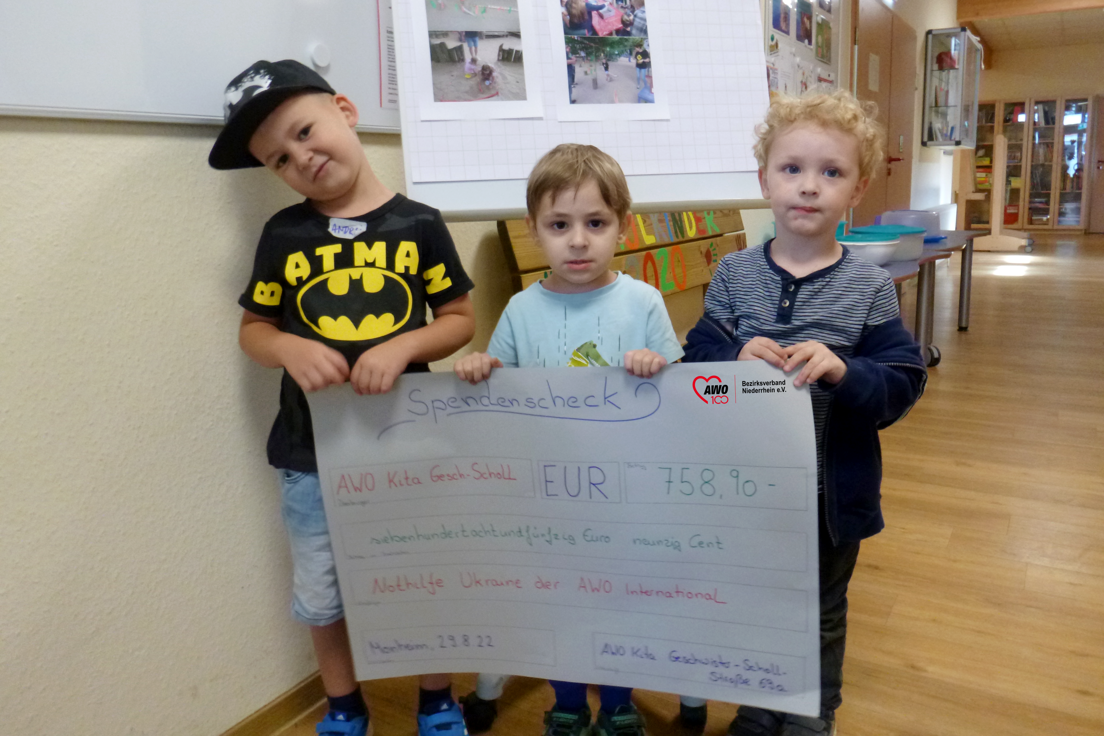 Das Bild zeigt Kita-Kinder mit einem Spendenscheck