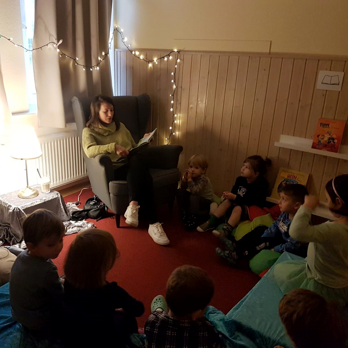 Das Foto zeigt eine Vorlesepatin beim Vorlesen in der Kita