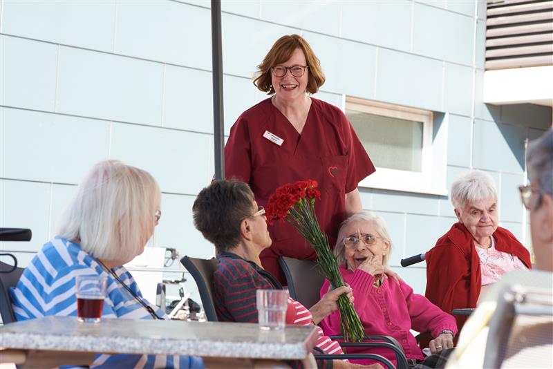 Auf diesem Bild ist eine Mitarbeiterin mit Bewohnerinnen zu sehen.