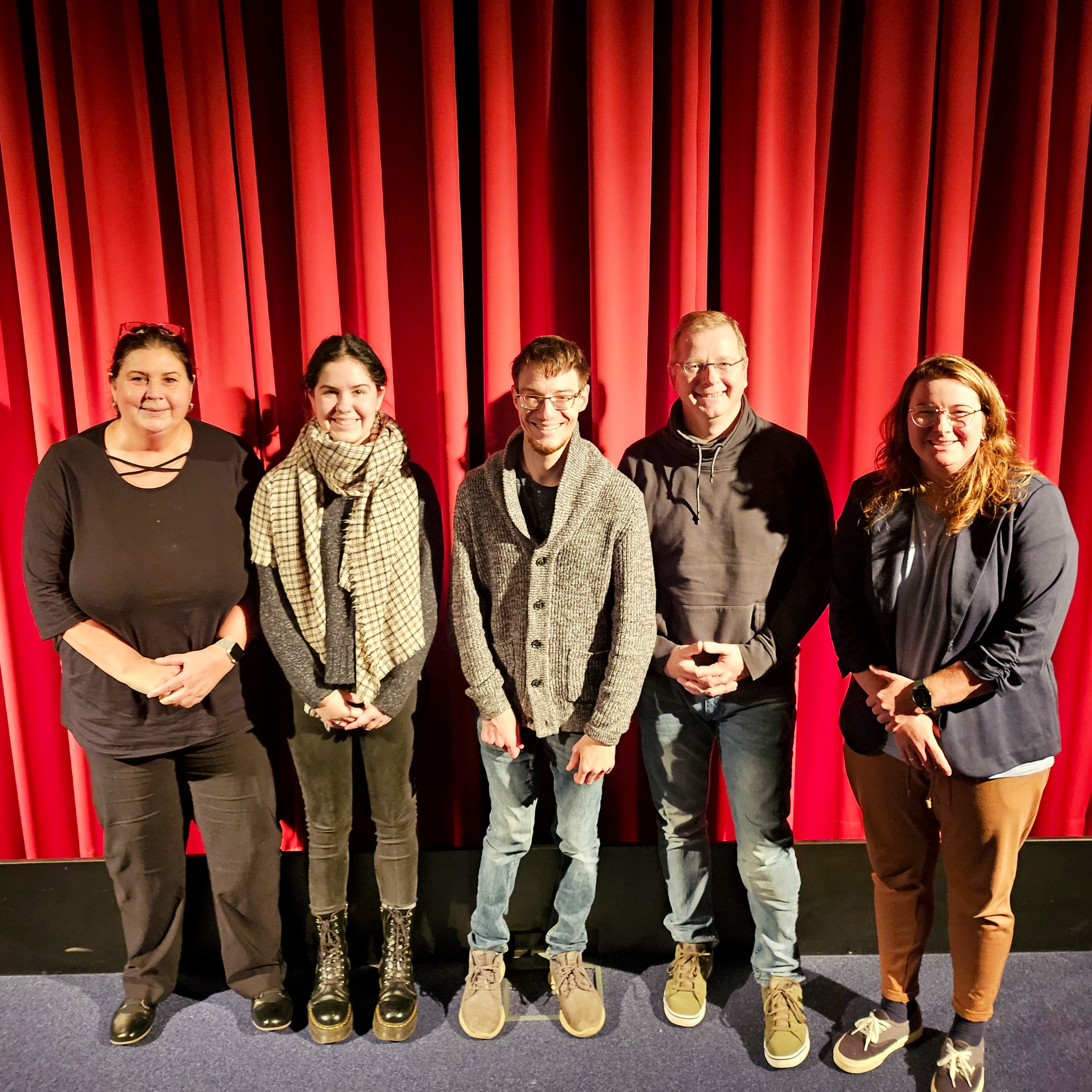 Das Foto zeigt die genannten Personen vor der Kinoleinwand